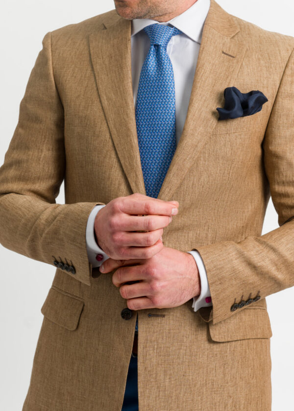 A striking men's tan linen jacket with 4 button cuff , styled with a white shirt and blue tie.